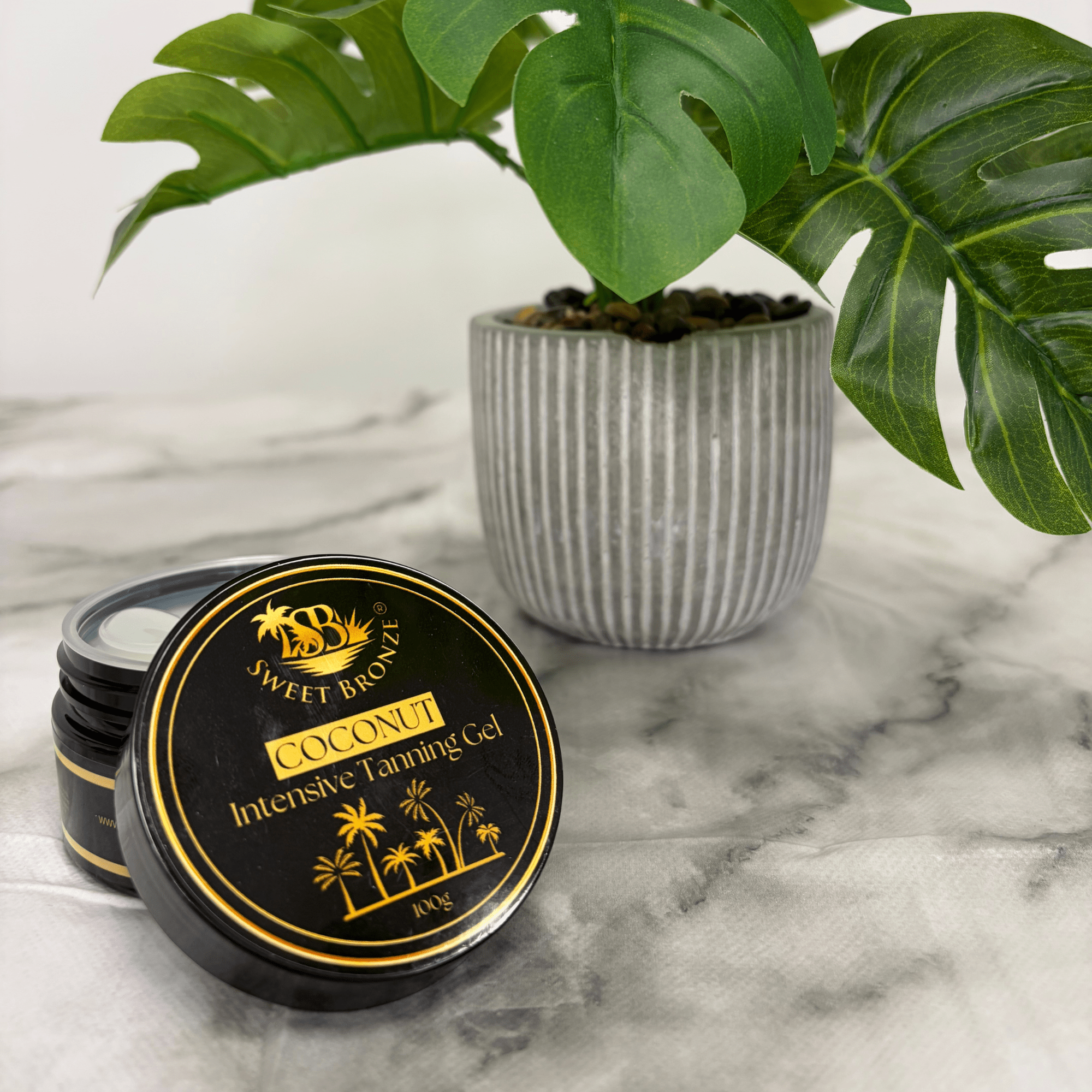 Tanning gel container with a plant in the background on a marble surface