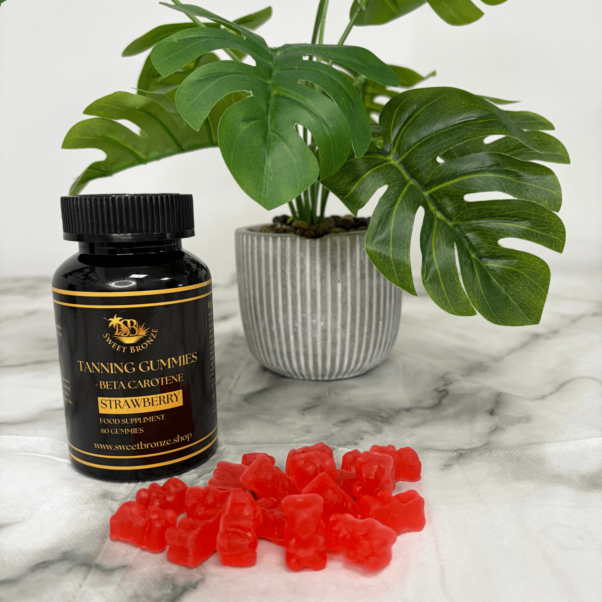 Tanning gummies and bottle on a marble surface with a plant in the background