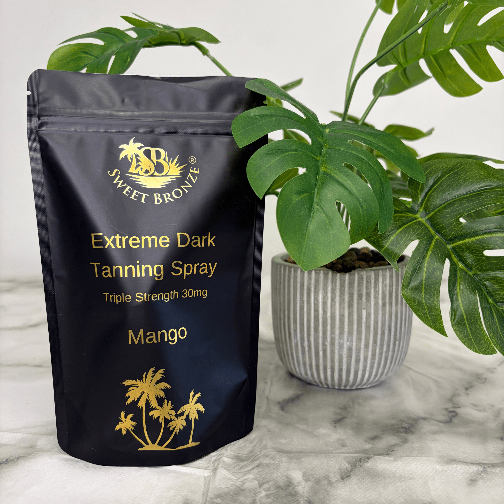 Sweet Bronze Extreme Dark Tanning Spray package with a plant in the background