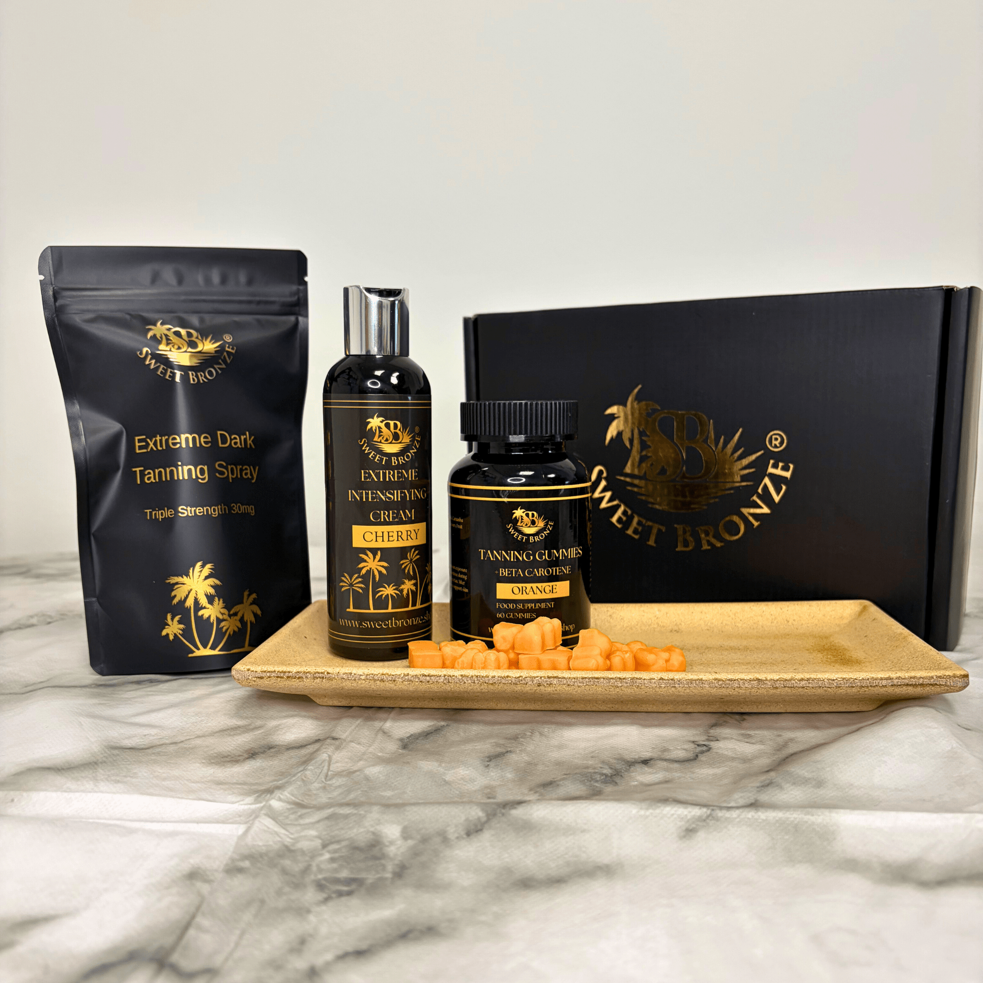 Sweet Bronze tanning products including spray, cream, and gummies on a marble surface.